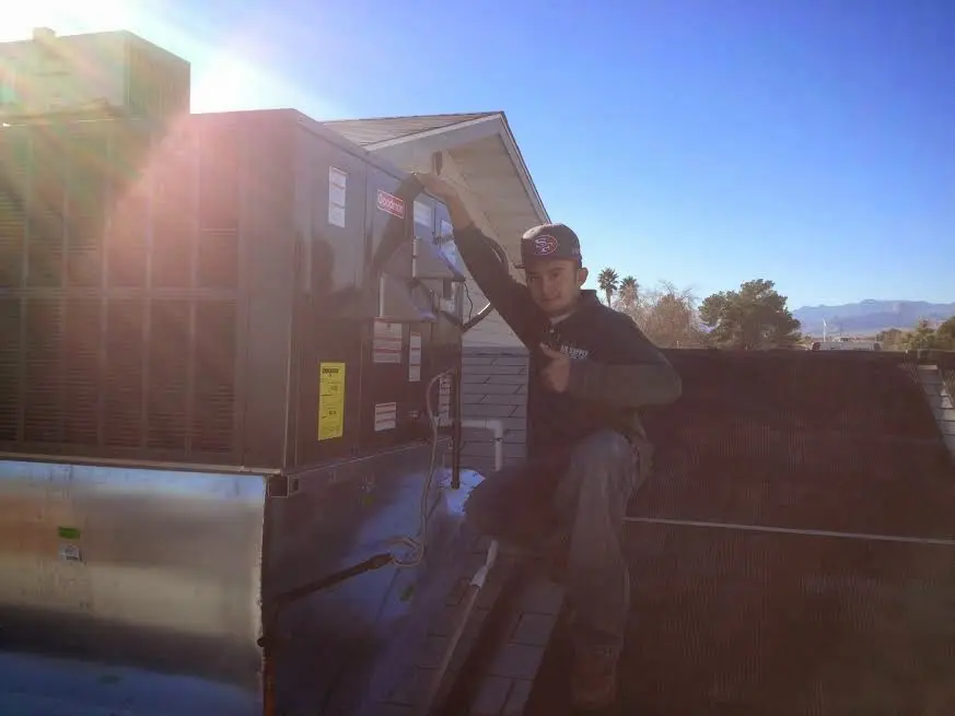 HVAC technician performing AC Tune-Up on a rooftop unit in Hobbs